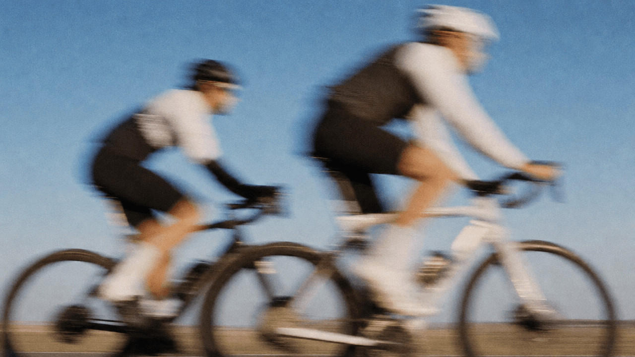 Two cyclists caught mid-ride against an open sky